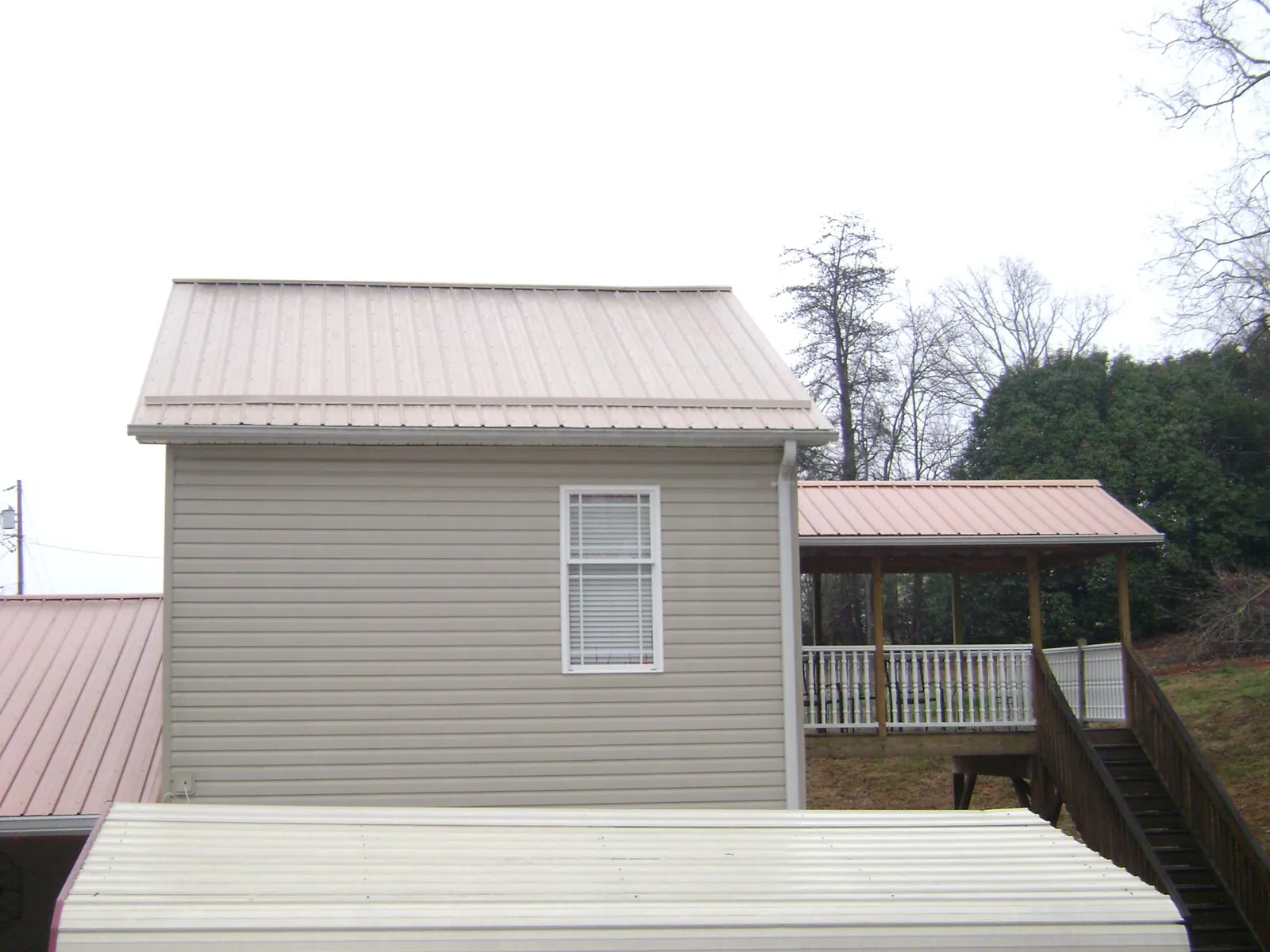Tan metal roofs on a two story addition and attached porch, from a Roof Replacement job in Bethlehem